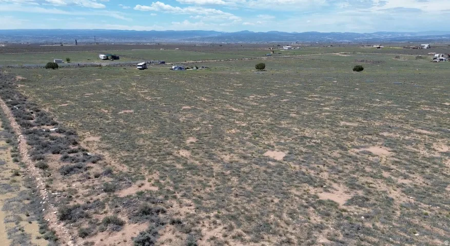 Expansive undeveloped land featuring sparse vegetation and distant mountain ranges
