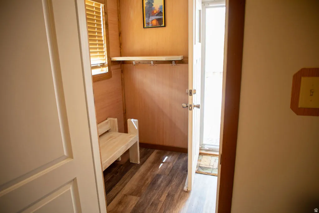 Entryway with wood-finish flooring, a built-in wooden bench, and a mounted shelf with coat hooks