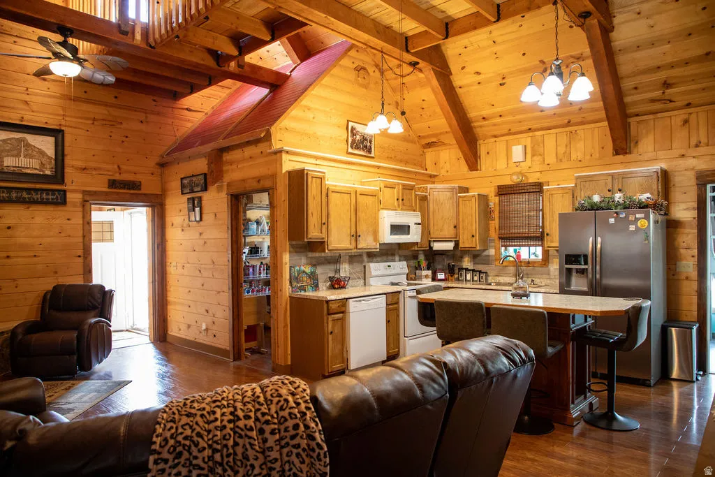 Open-concept kitchen and living area featuring extensive wood paneling, exposed wood beams, and wood-finish flooring