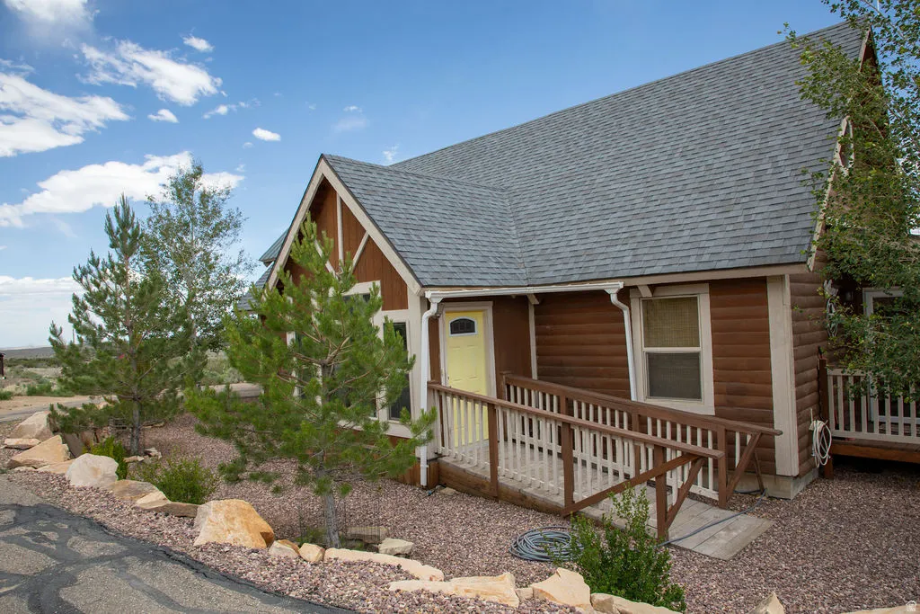 Brown siding exterior featuring a light gray shingle roof and a vibrant yellow entry door