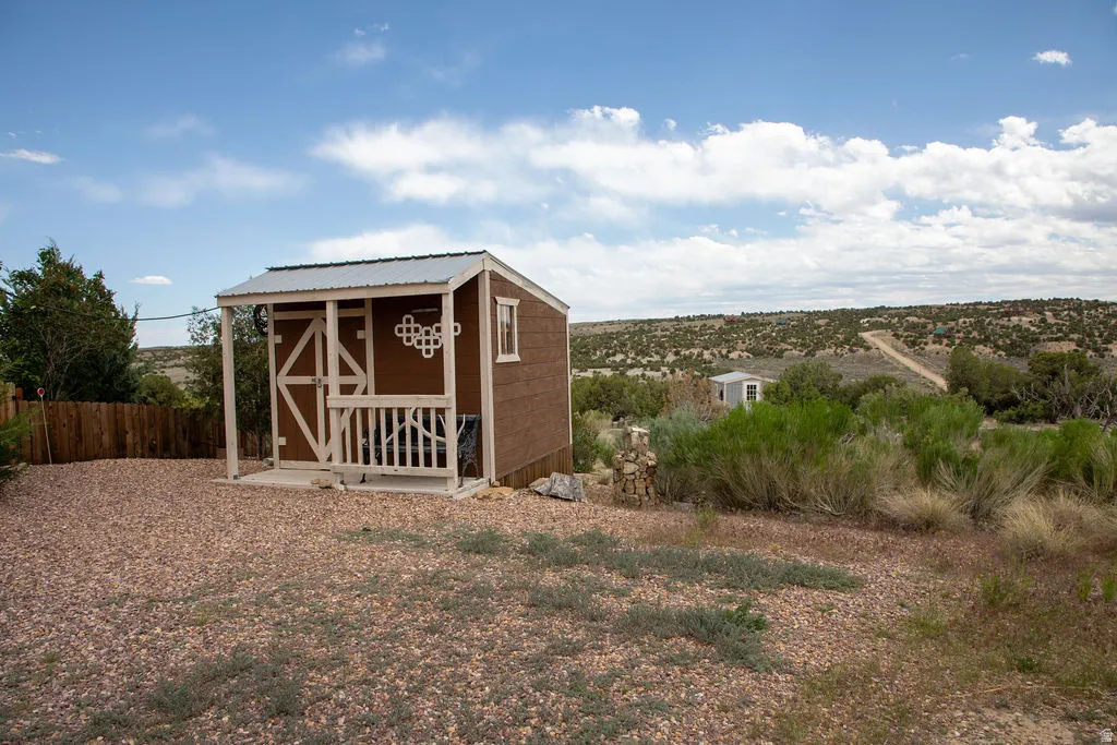 Detached outbuilding featuring a covered porch, white railing, and exterior wall decor