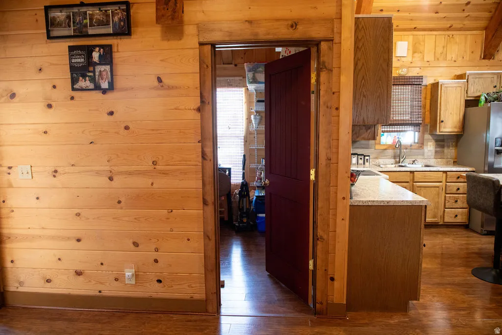 Warm wood-paneled walls featuring a rich red interior door and contrasting wood-finish flooring