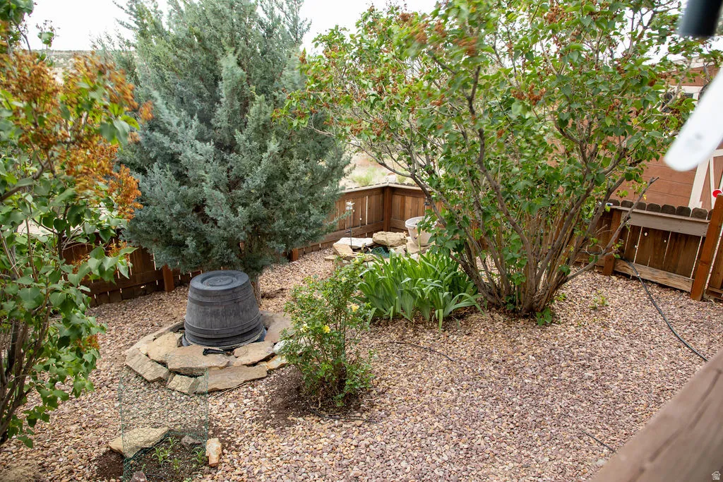 Landscaped backyard featuring gravel ground cover, a natural rock water feature, a variety of mature shrubs, and evergreen trees