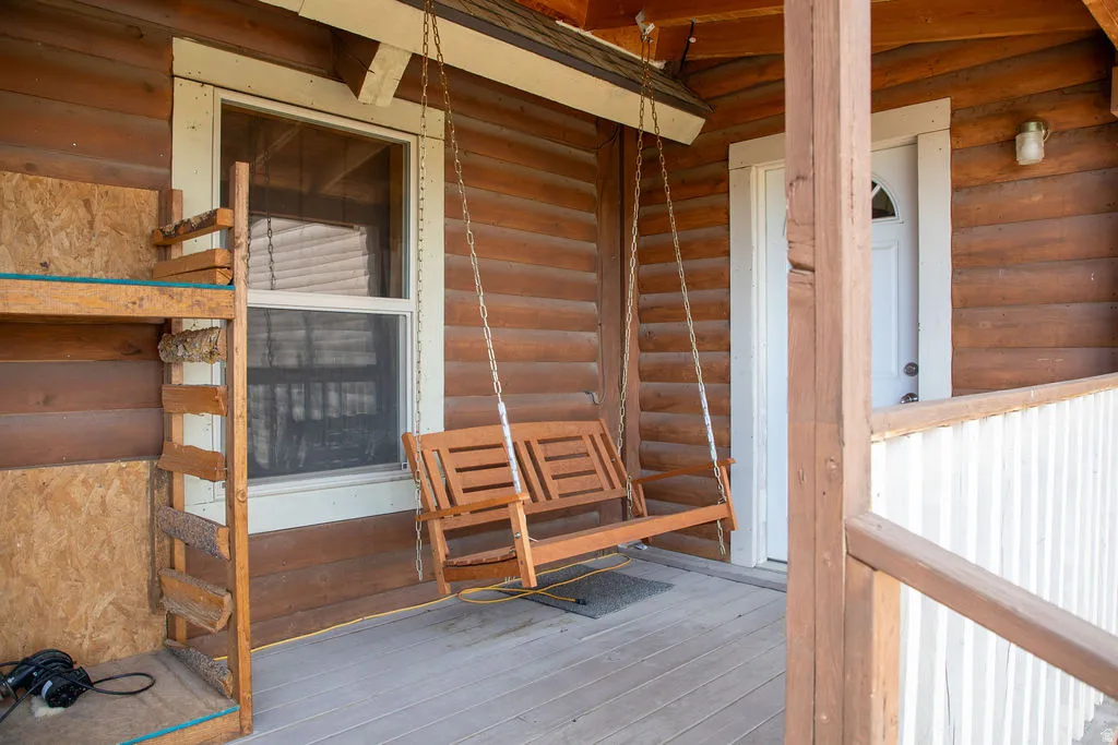 Wood-plank exterior featuring a covered porch with a wood-finish floor and a porch swing