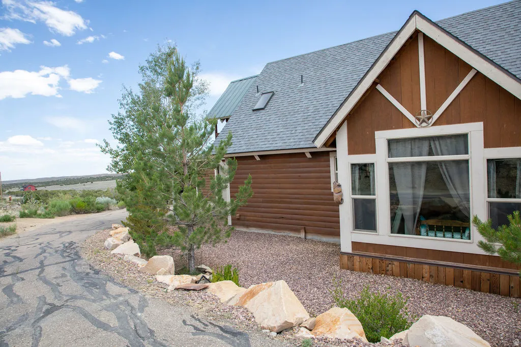 Brown log siding exterior with a light gray shingle roof and a prominent white-trimmed window