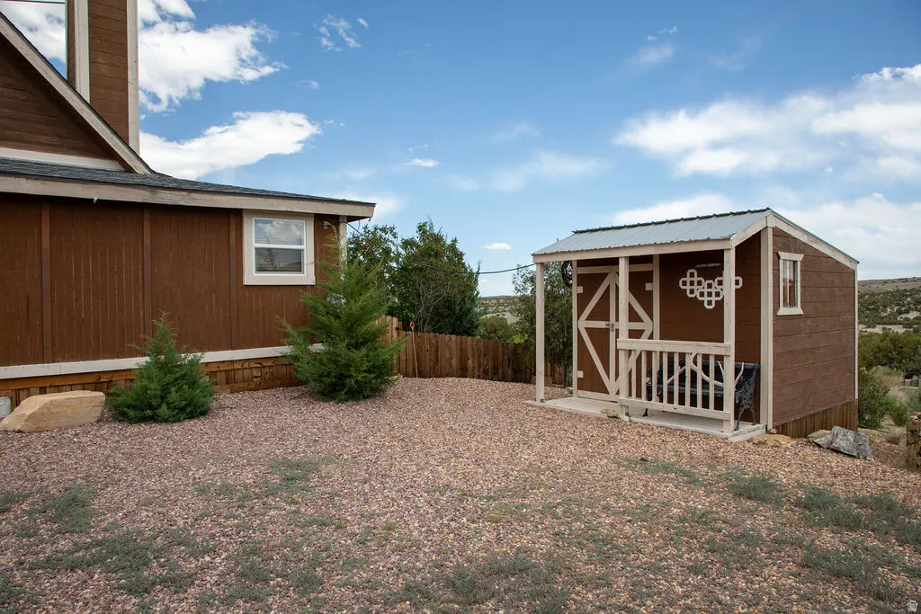 Detached shed featuring a covered porch, metal roof, and wood siding