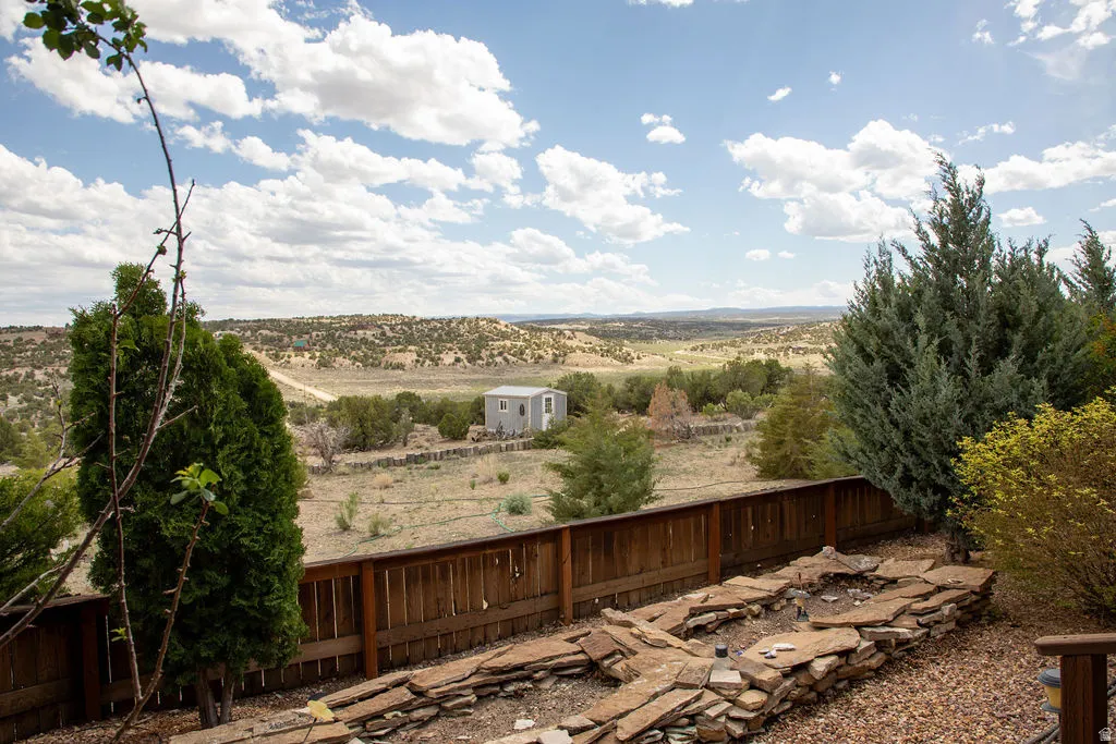 Expansive outdoor space featuring a large wooden fence, mature evergreen trees, and a flagstone-lined area