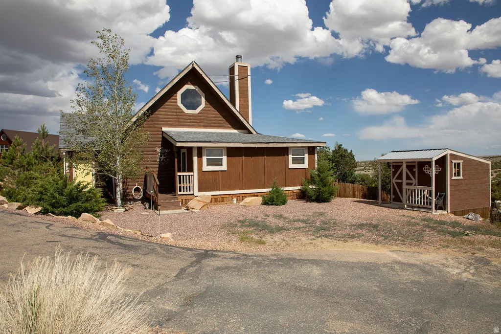 Brown-sided home featuring a prominent octagonal window and a covered front entry