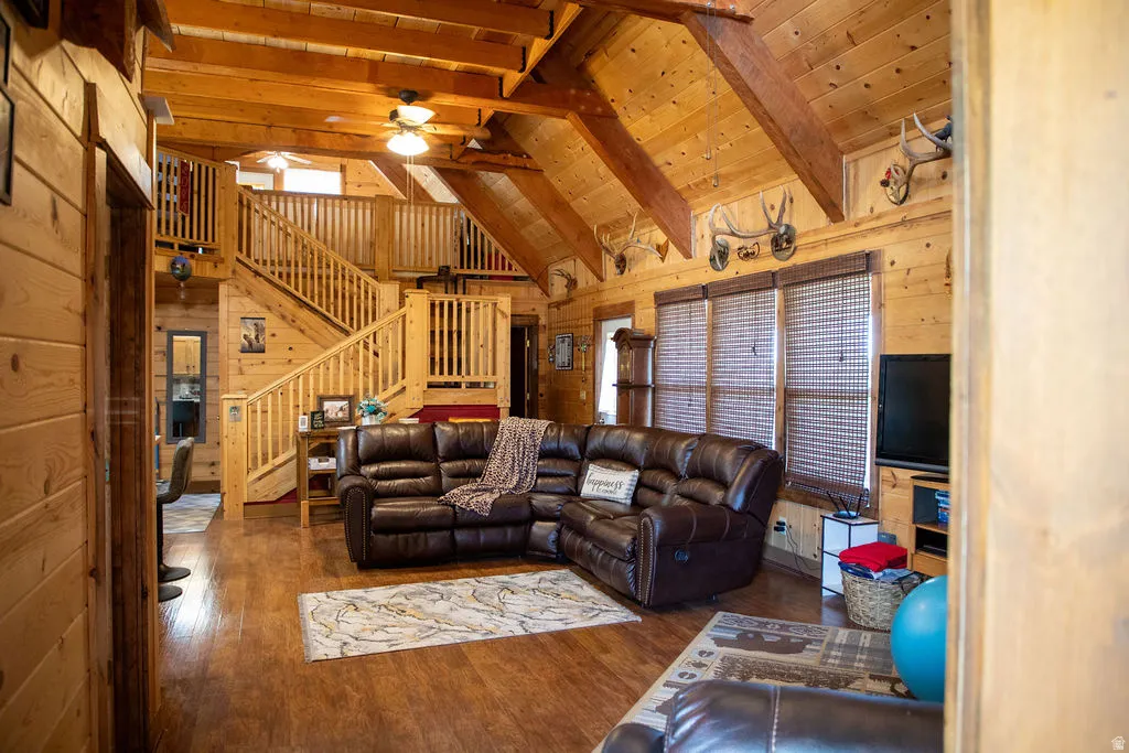Spacious living area featuring extensive wood-finish walls and ceilings, exposed wood beams, and wood-finish flooring