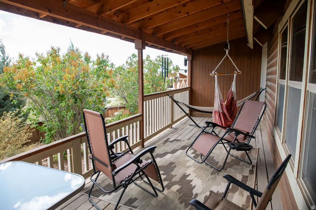 Covered outdoor deck with wood-plank flooring, wood ceiling with exposed beams, and a wood railing system