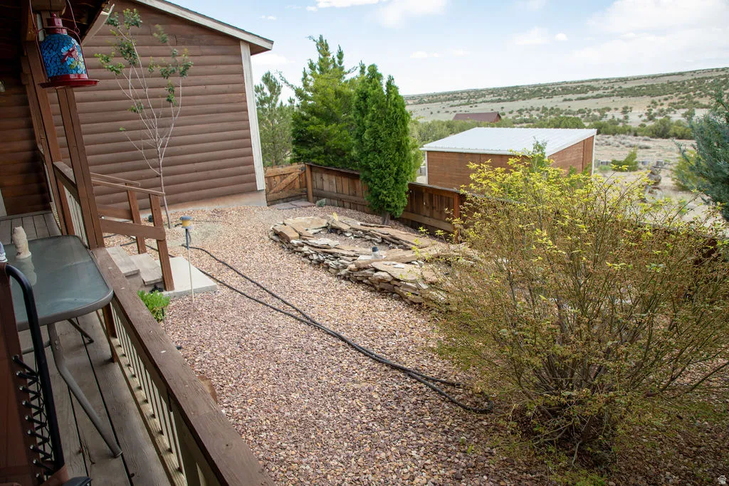 Wood-sided exterior featuring a covered porch with railings, a gravel yard, and a stone-lined fire pit