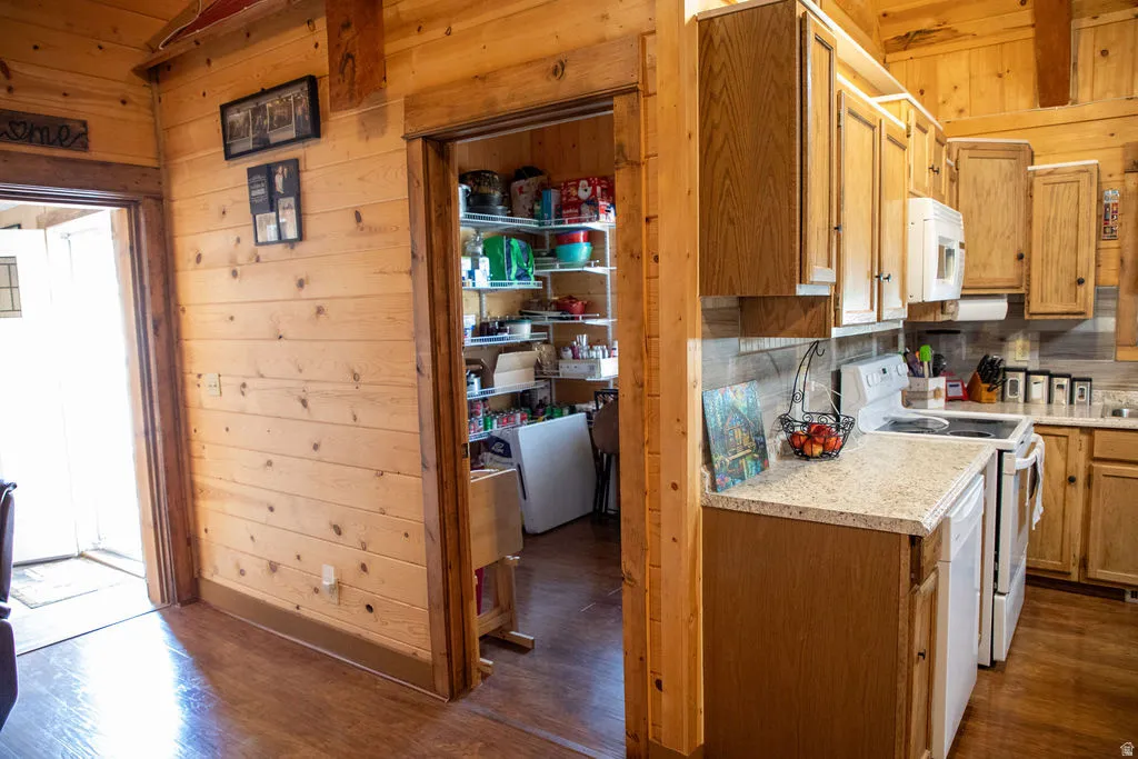 Kitchen featuring wood cabinetry, light-toned countertops, and white appliances