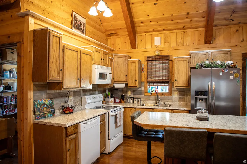 Kitchen featuring wood-paneled walls and ceiling, exposed wood beams, wood-finish cabinetry, light-toned countertops, and a full suite of appliances
