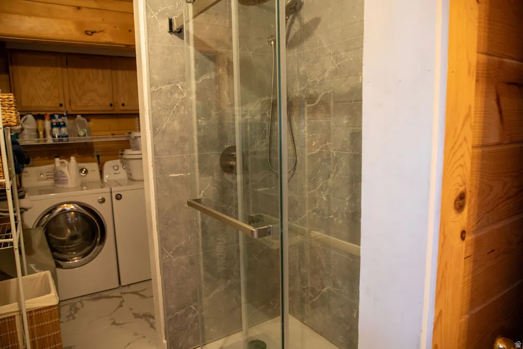 Glass-enclosed shower with a modern gray-veined tile surround, brushed nickel fixtures, and a clear glass door