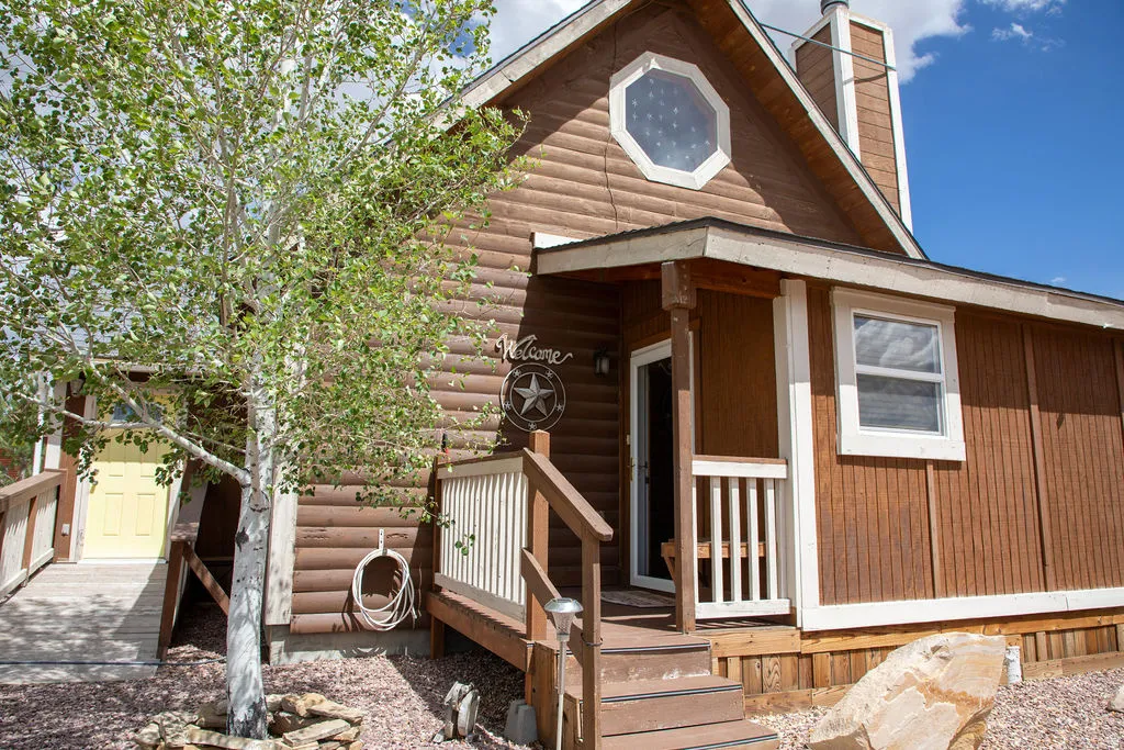 Wood-sided exterior featuring a covered porch, white railing, and a multi-level wooden entrance