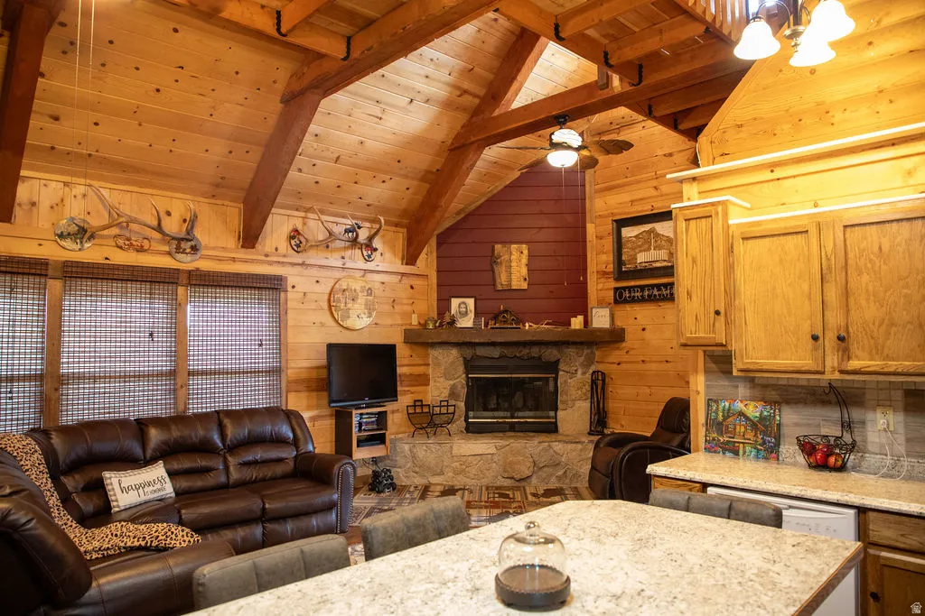 Vaulted wood-paneled ceilings with exposed beams, a stone fireplace, and wood-paneled walls define this space