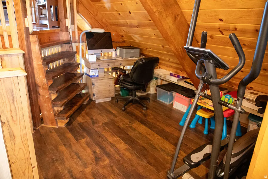 Wood-finish flooring throughout this area featuring natural wood plank walls and a sloped ceiling