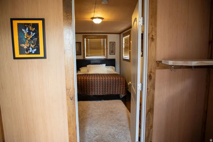 Bedroom space featuring wood-finish walls and doorframes, a ceiling-mounted light fixture, and horizontal window blinds