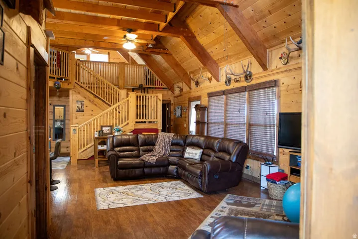 Spacious living area featuring extensive wood-finish walls and ceilings, exposed wood beams, and wood-finish flooring