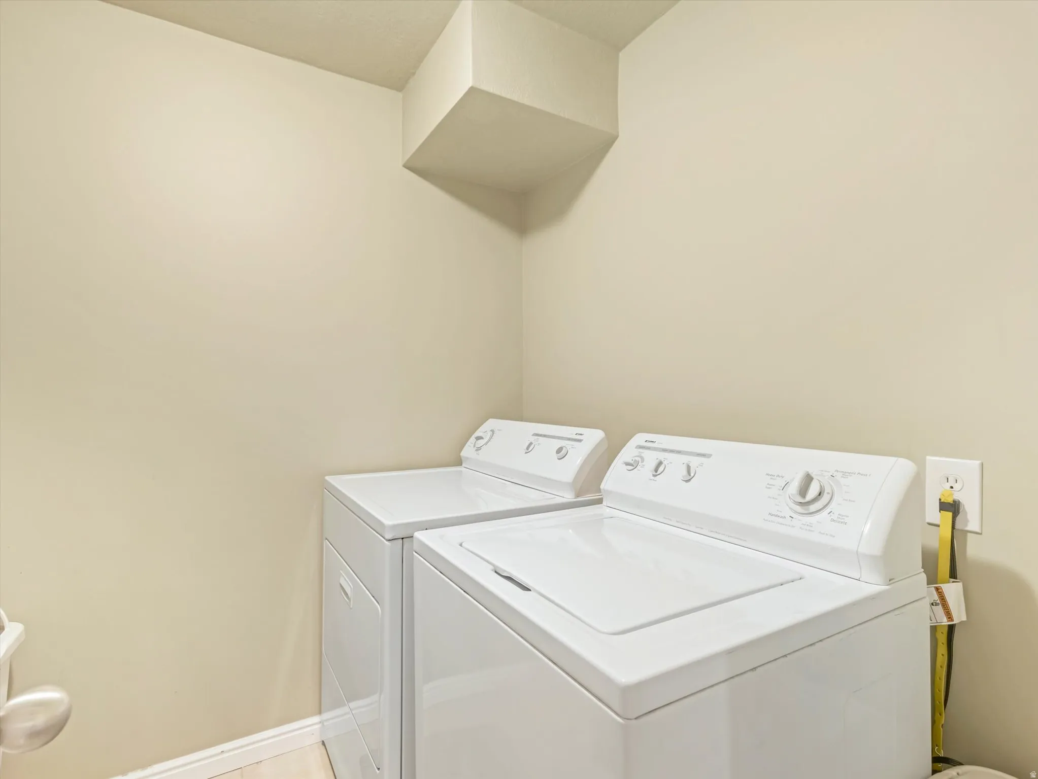 Dedicated laundry area featuring a white top-load washing machine and dryer, neutral wall paint, and light-toned flooring
