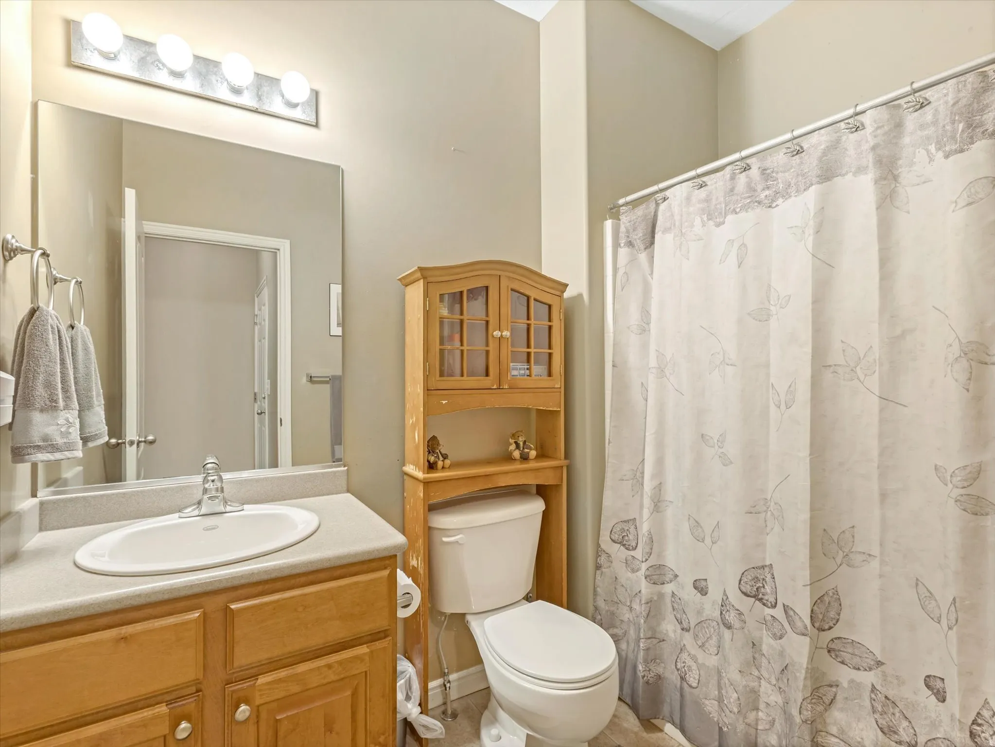 Bathroom featuring a wood vanity with an integrated sink, a rectangular mirror, and a wall-mounted light fixture