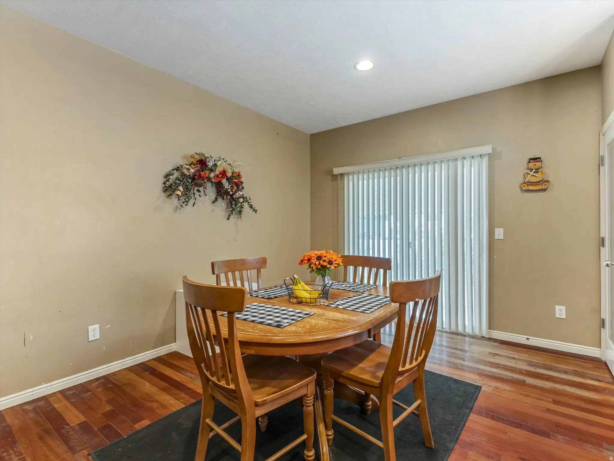 Dining area featuring wood-finish flooring, recessed ceiling lighting, and a sliding glass door with vertical blinds