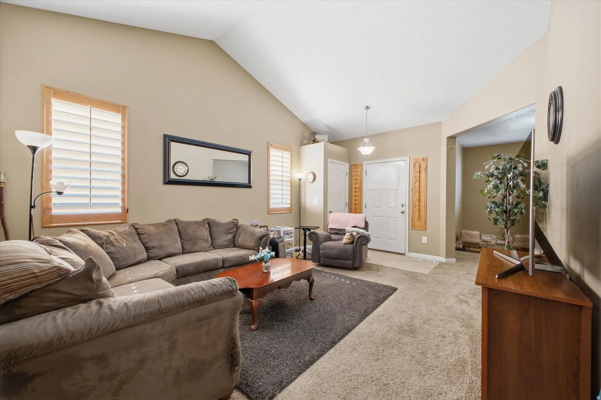 Living area featuring vaulted ceilings and neutral-toned carpeting