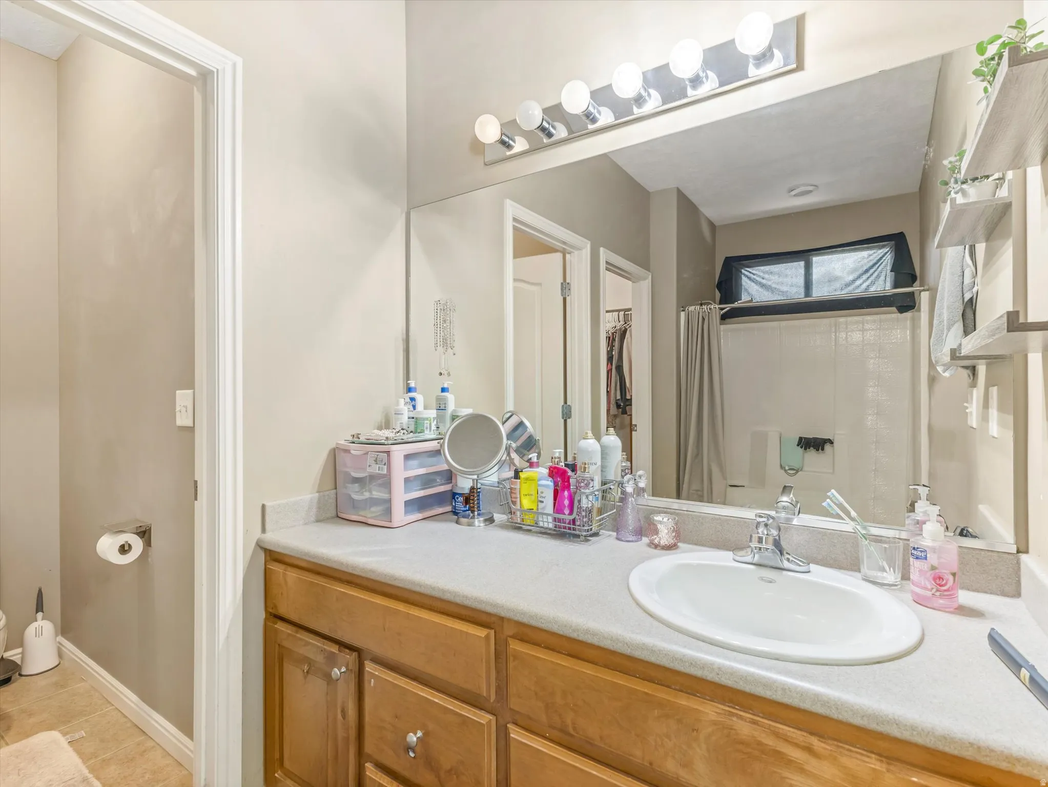 Bathroom vanity featuring a light-toned countertop, an integrated sink, and wood-finish cabinetry