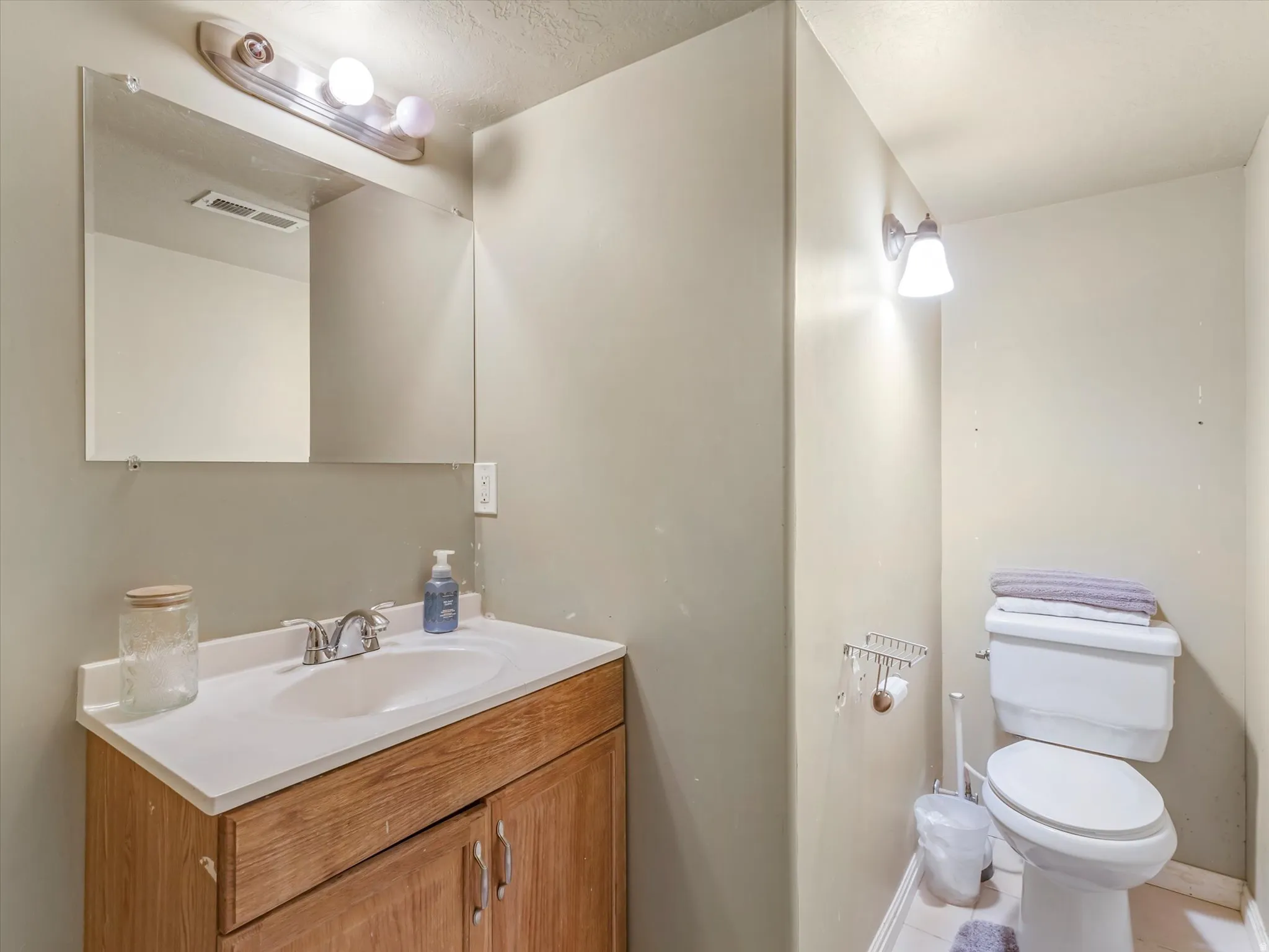 Bathroom vanity featuring a white countertop with an integrated sink, wood-finish cabinetry, and a chrome faucet