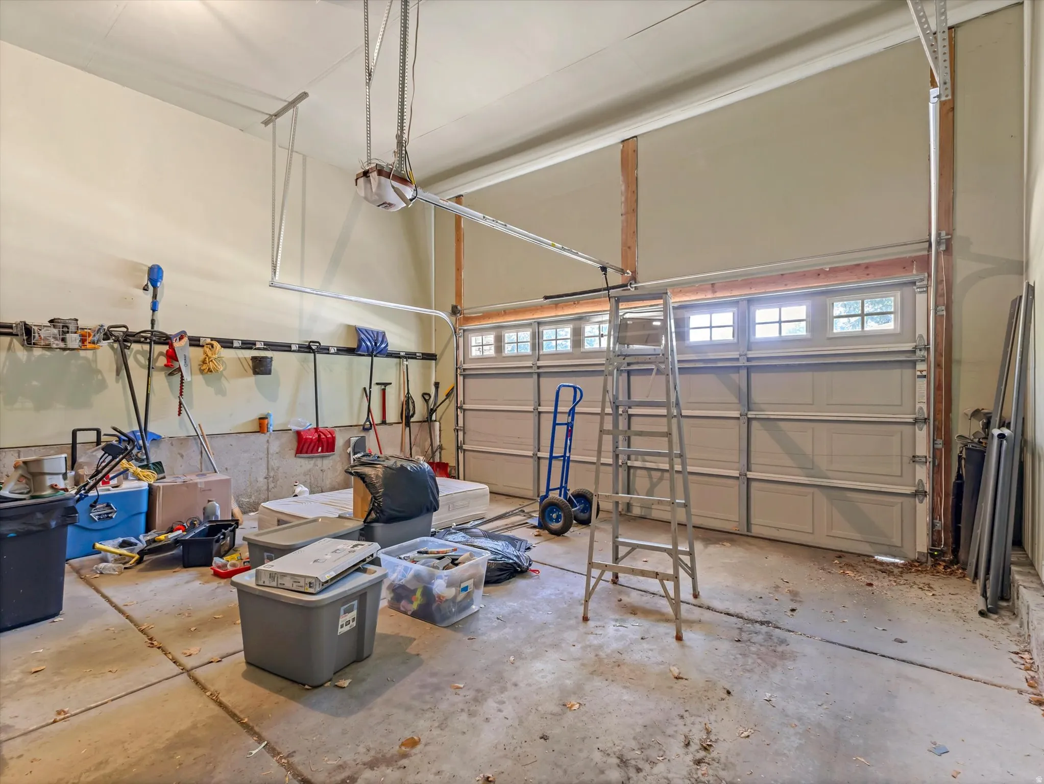Spacious garage featuring two overhead doors with window accents, concrete flooring, and an automatic garage door opener