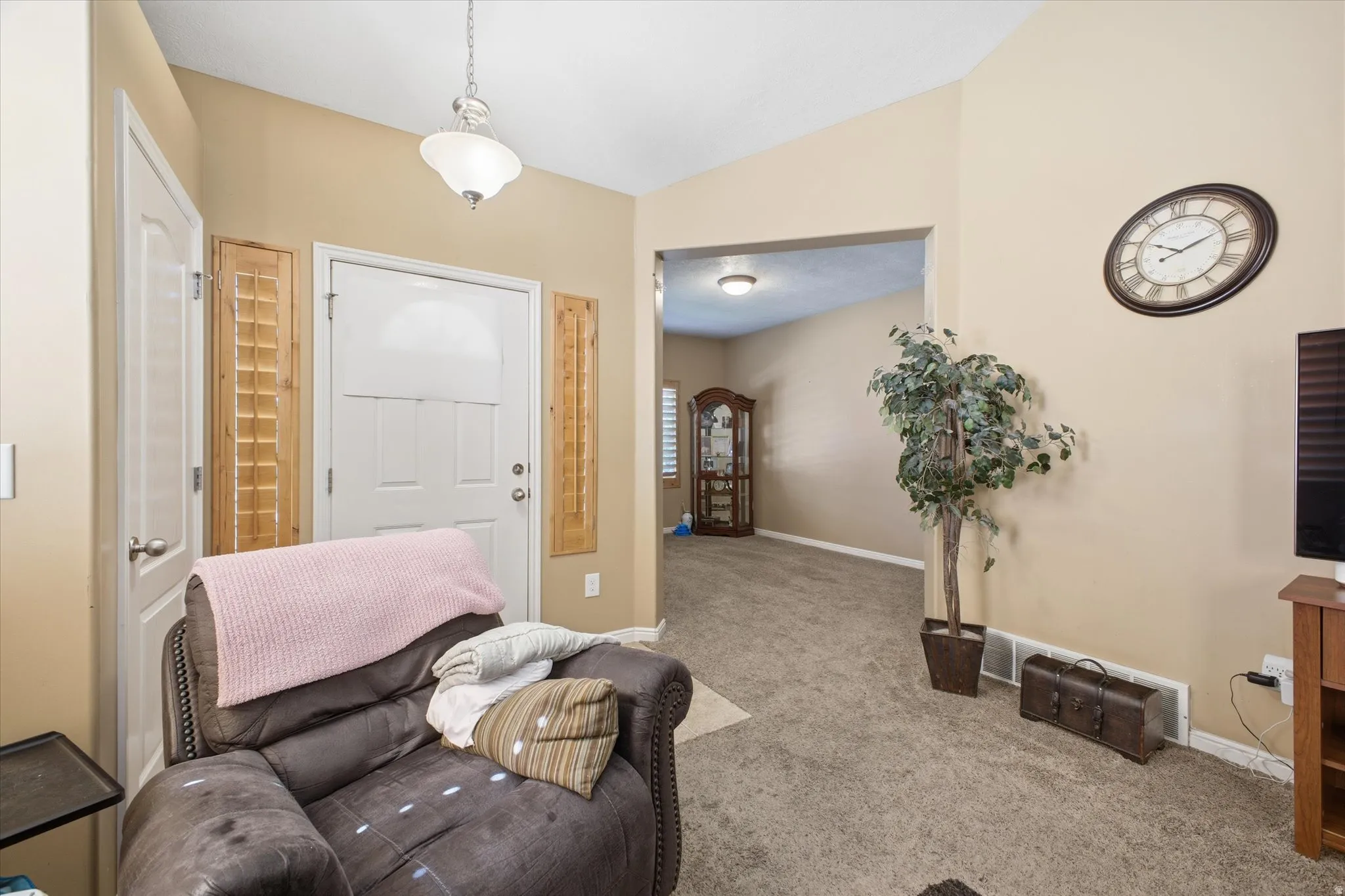 Entryway featuring a paneled front door, vaulted ceiling, and an archway opening to a carpeted interior