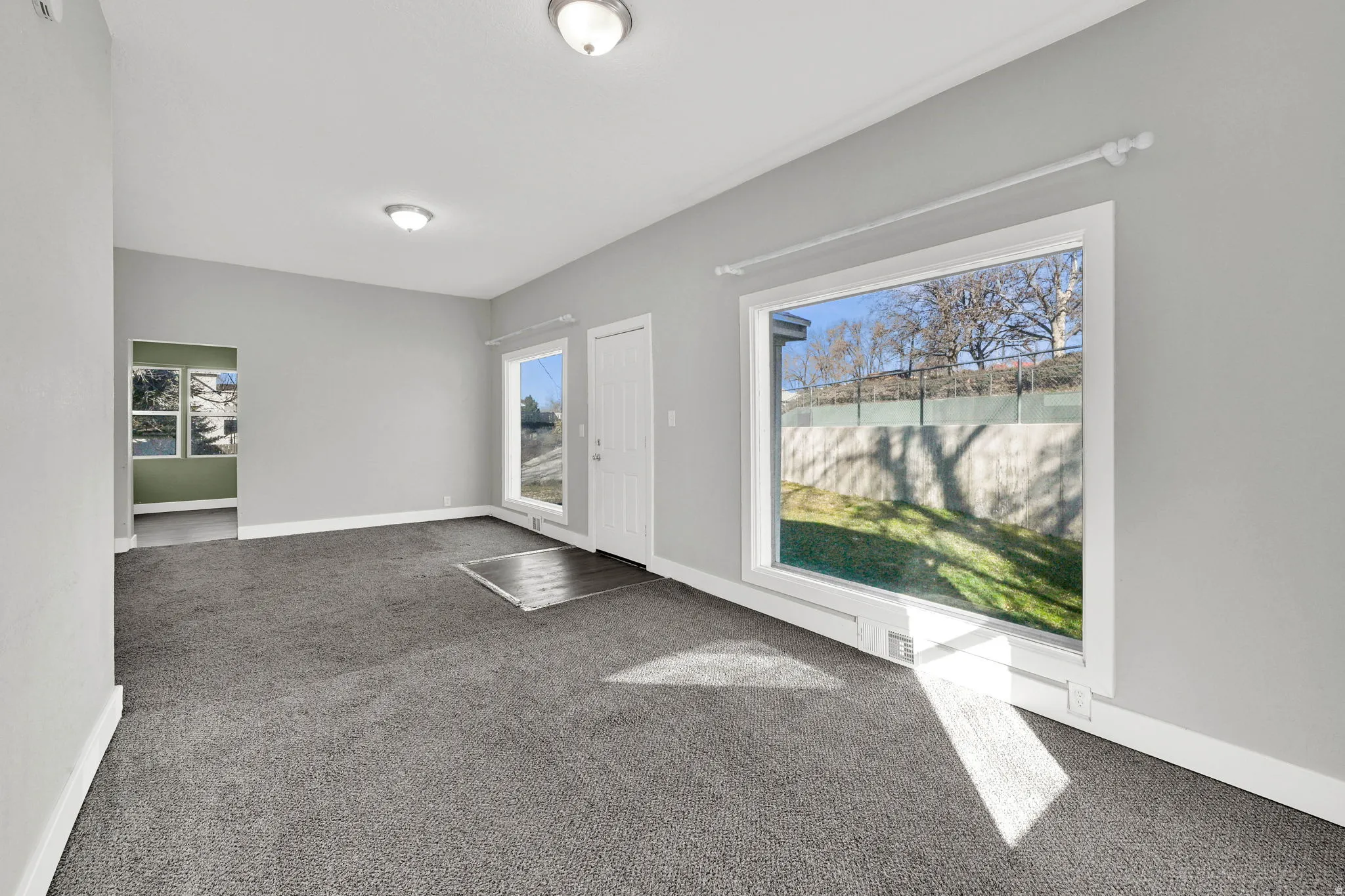 Spacious room featuring neutral grey walls and dark grey carpeting