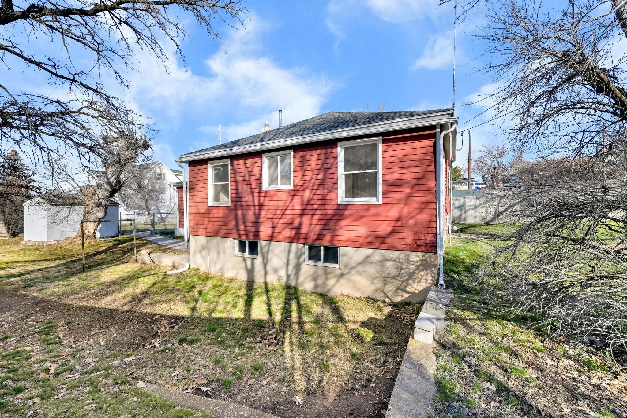 Red siding exterior with a dark shingle roof and white window trim