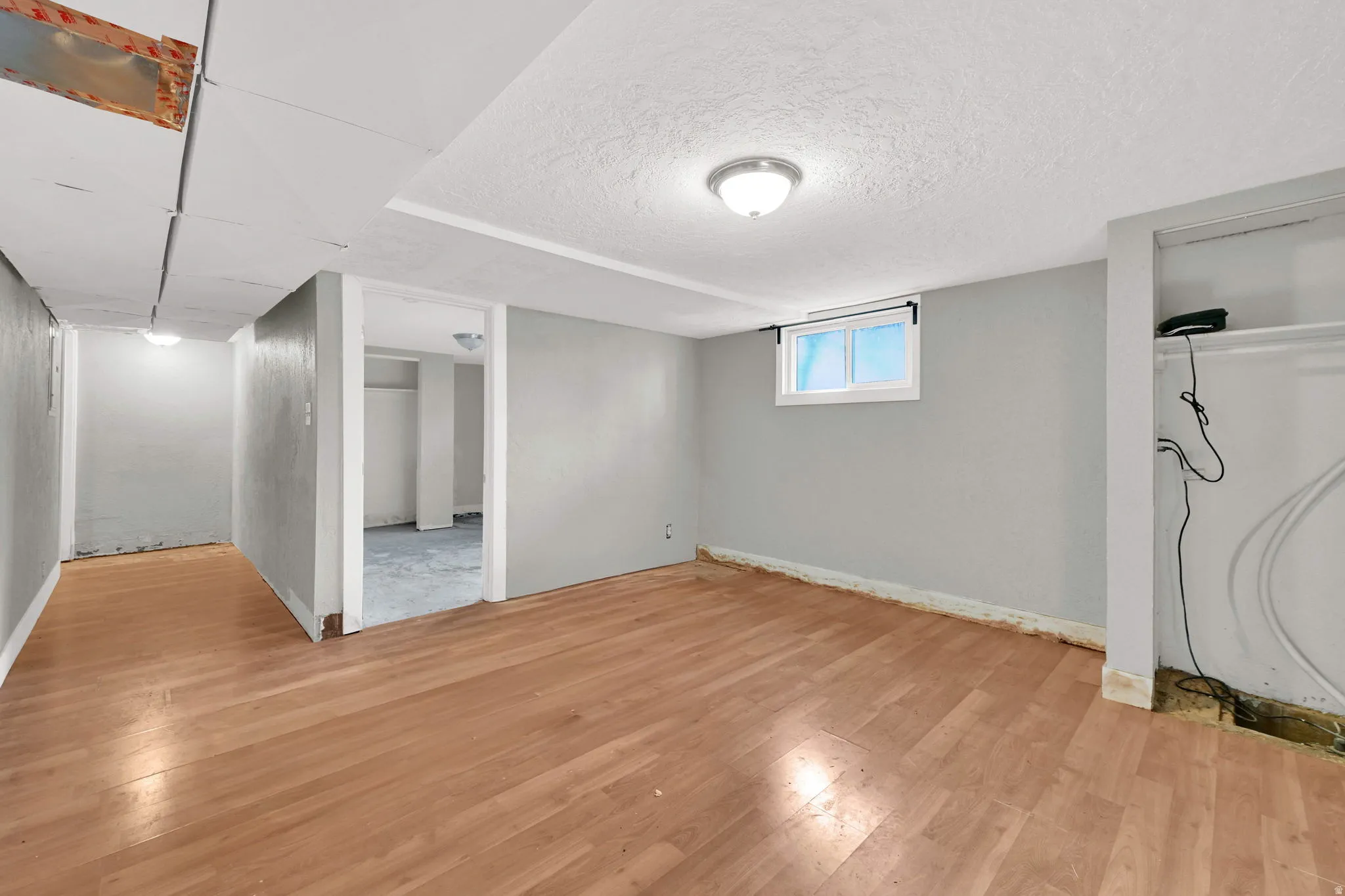 Open concept room with wood-finish flooring, light grey walls, and a recessed window