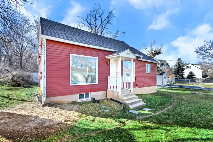 Red siding exterior with a dark shingle roof, featuring a covered entry porch with white railings and steps