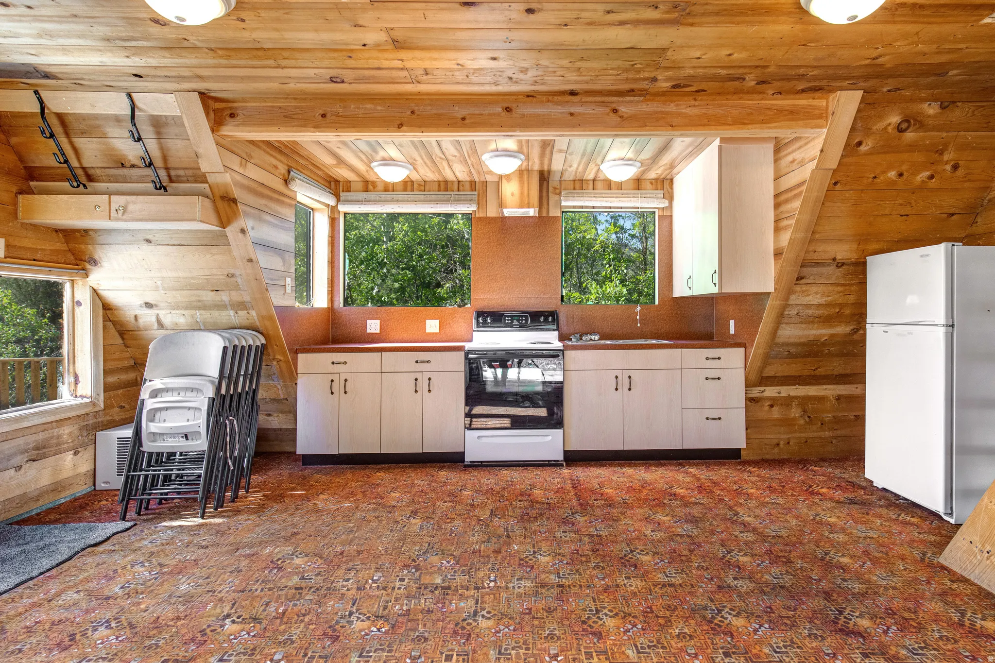 Wood-paneled room featuring a kitchen area with white cabinetry, a white range, and a white refrigerator