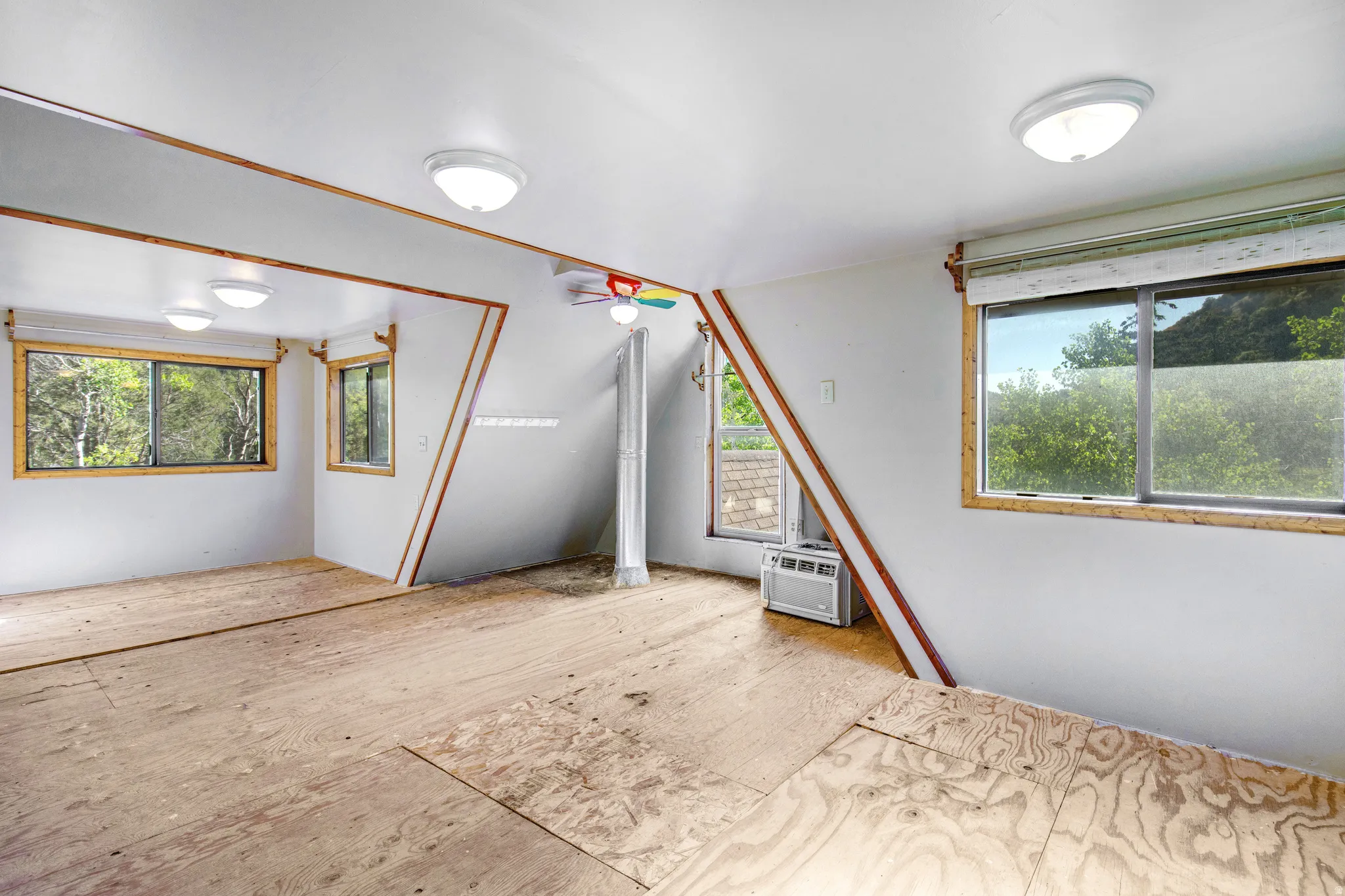 Spacious room with white walls and exposed plywood subflooring