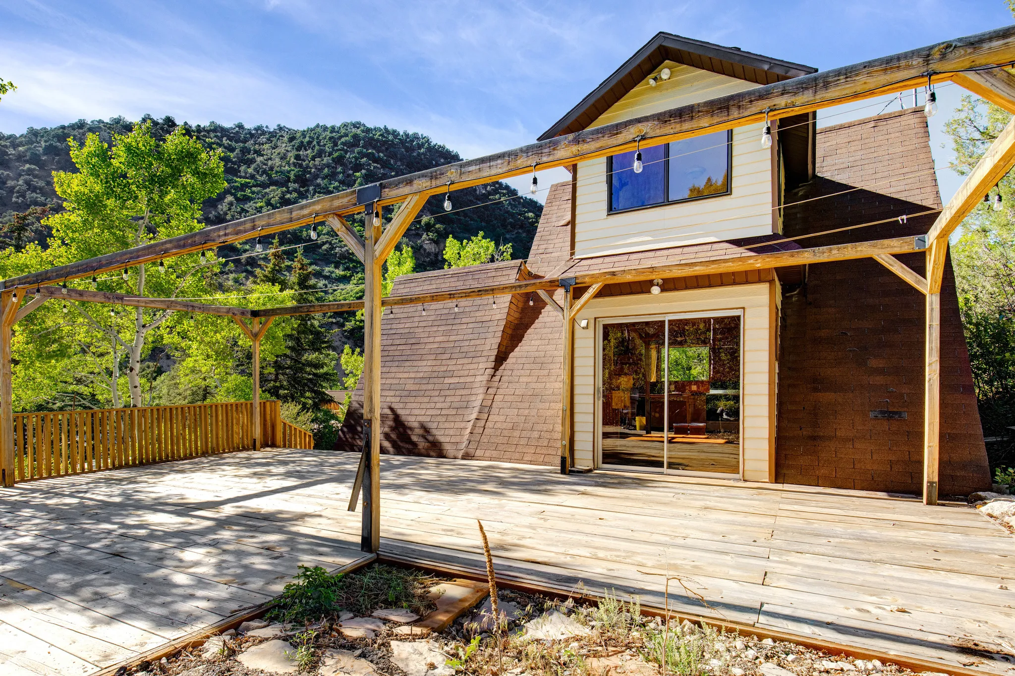 Expansive outdoor wood decking featuring a wood pergola with string lighting