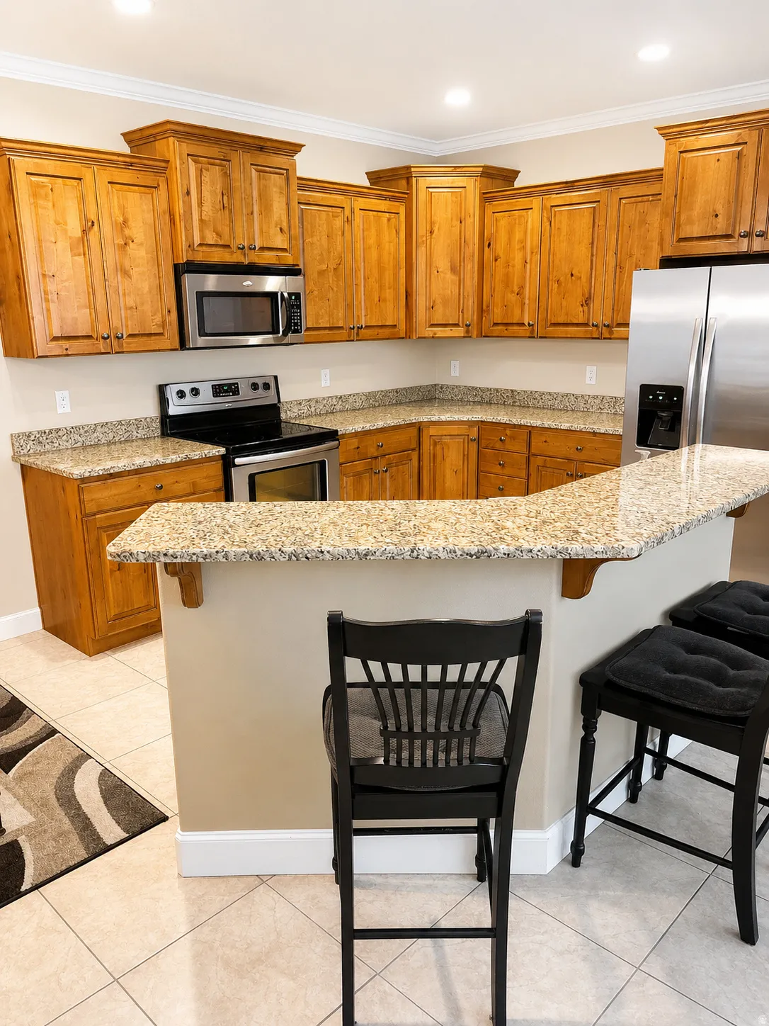Kitchen featuring wood cabinetry, stainless steel appliances, granite countertops, and a breakfast bar