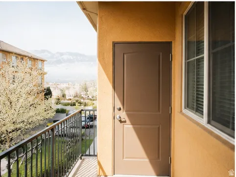 Private balcony featuring black wrought iron railing, stucco exterior, and a solid panel door