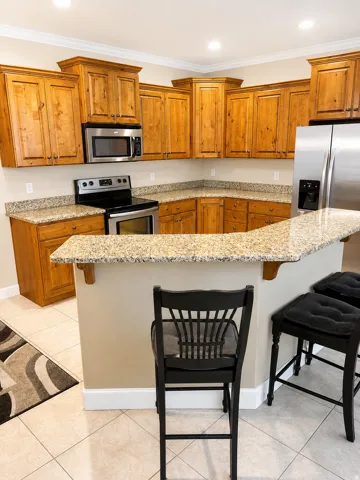 Kitchen featuring wood cabinetry, stainless steel appliances, granite countertops, and a breakfast bar