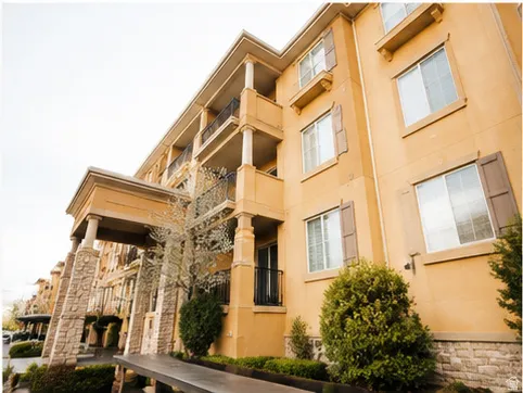 Multi-story building featuring a stucco exterior with stone accents and decorative shutters