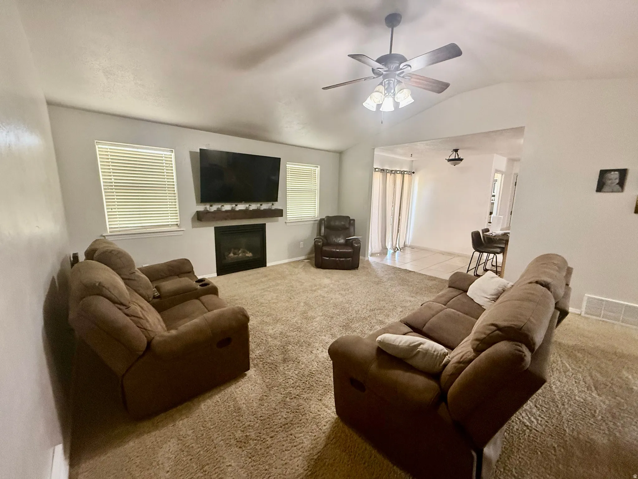 Living area featuring a vaulted ceiling and a ceiling fan with integrated lighting