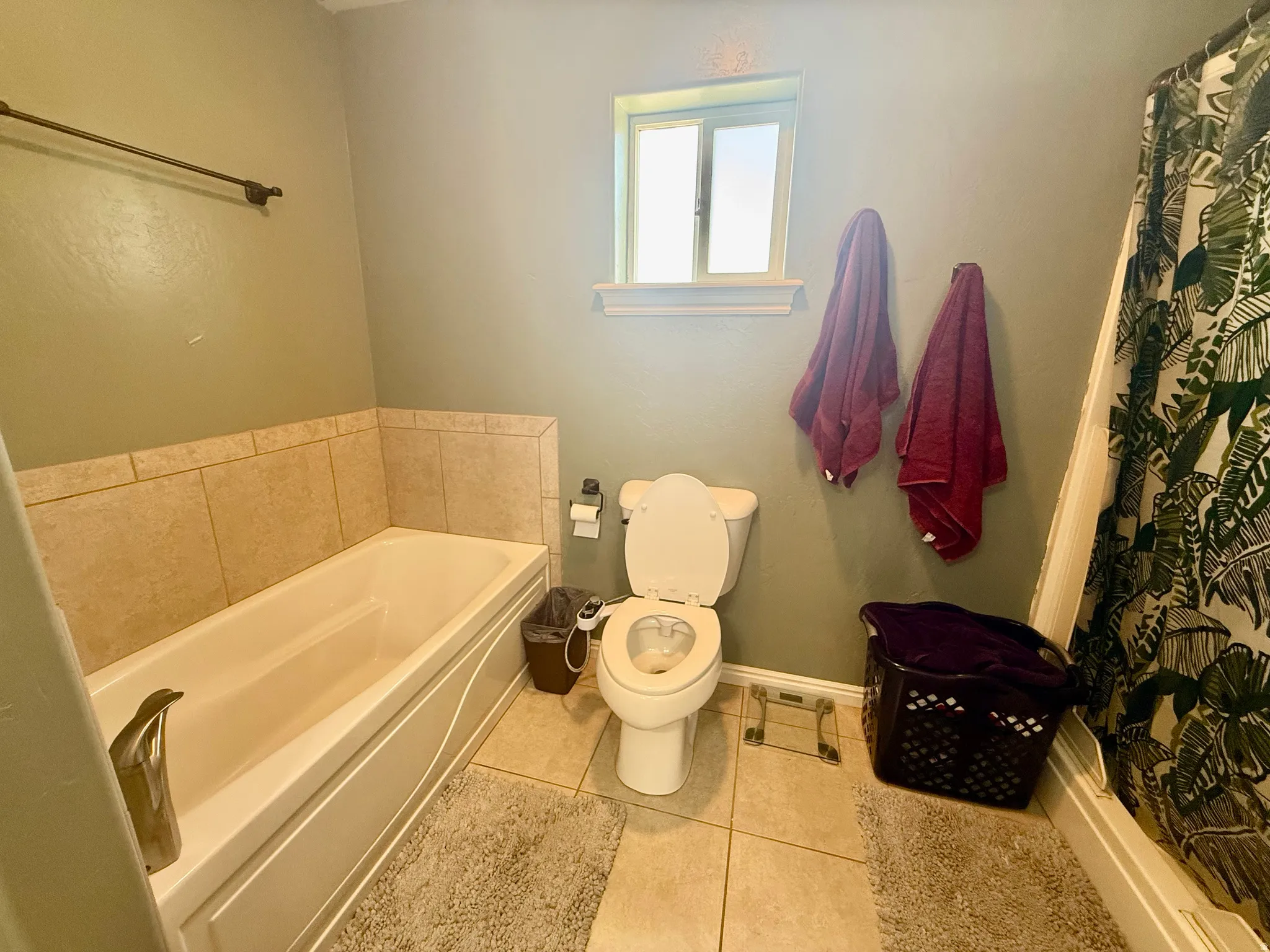 Bathroom featuring a built-in tub with tile surround, a window for natural light, and tile flooring