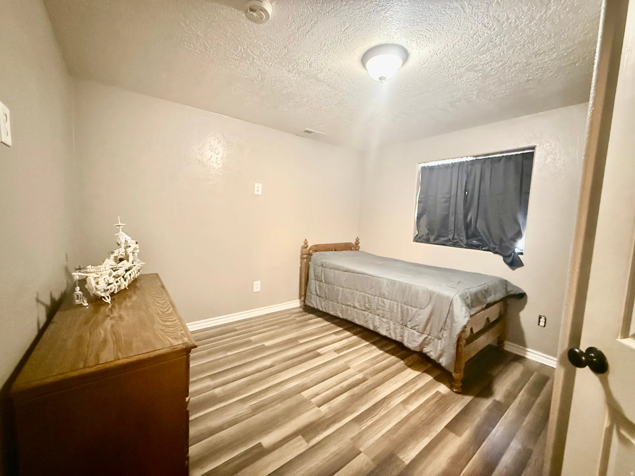 Room featuring wood-finish flooring, neutral wall paint, and white baseboards