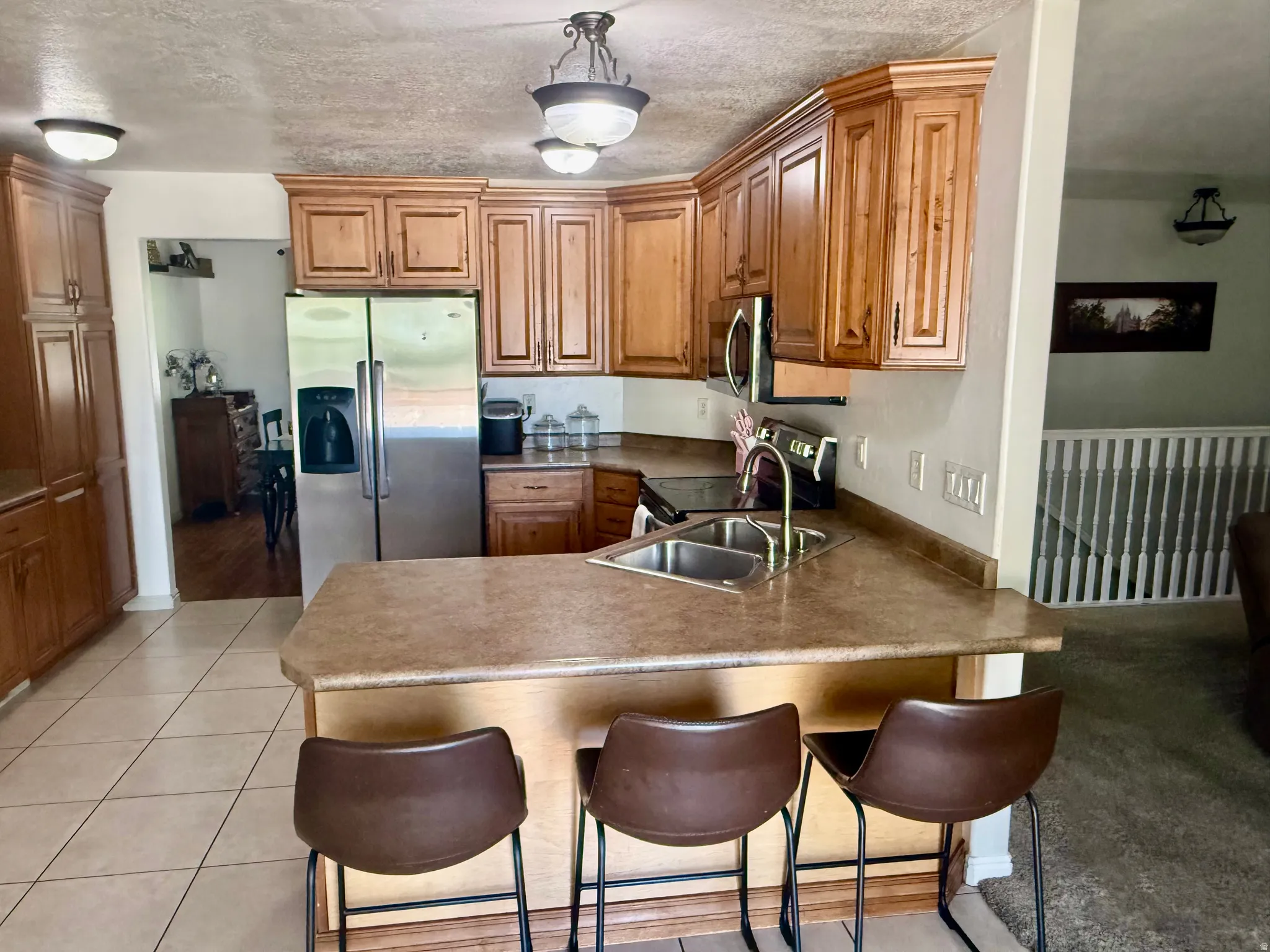 Kitchen featuring wood cabinetry, stone-look countertops, and stainless steel appliances