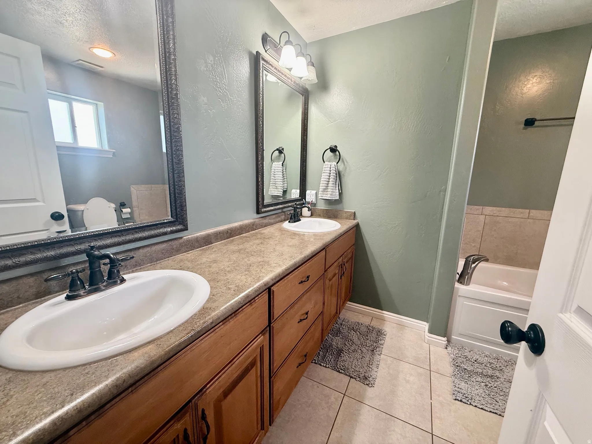 Dual vanity with wood-finish cabinetry and integrated sinks, complemented by framed mirrors