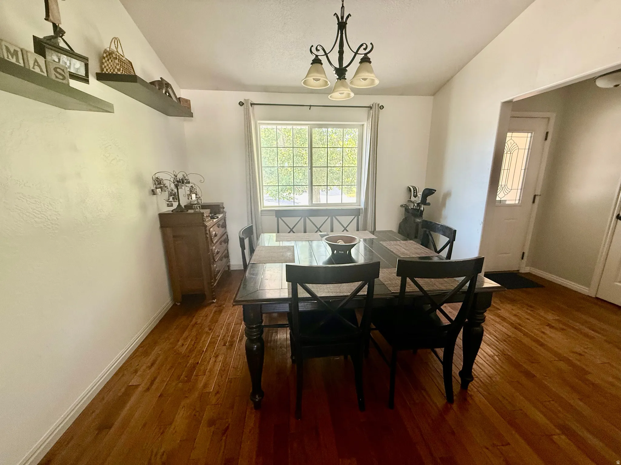 Dining area featuring wood-finish flooring, a window with exterior views, and a traditional chandelier