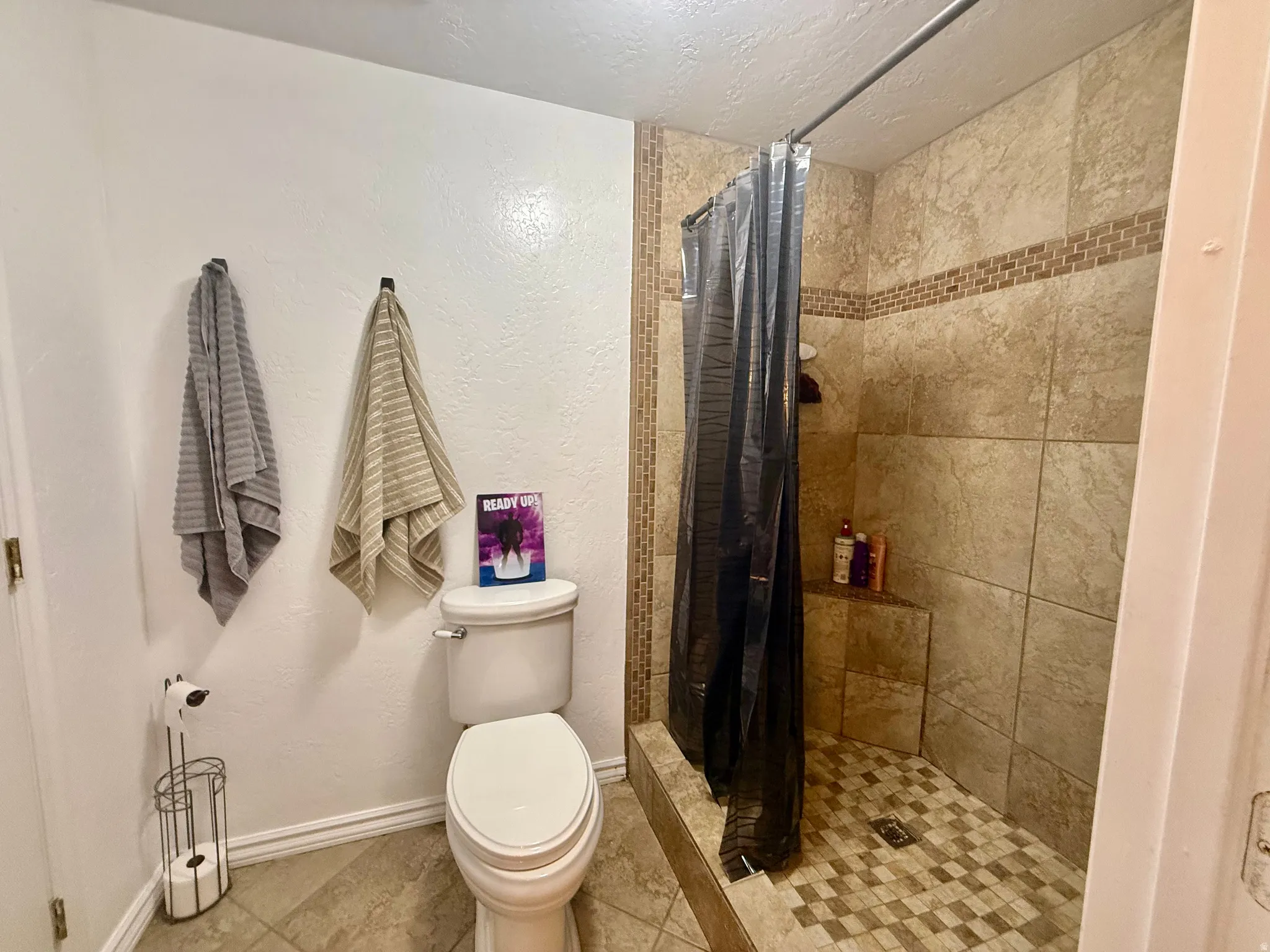 Tiled walk-in shower featuring a mosaic accent band and a built-in corner seat