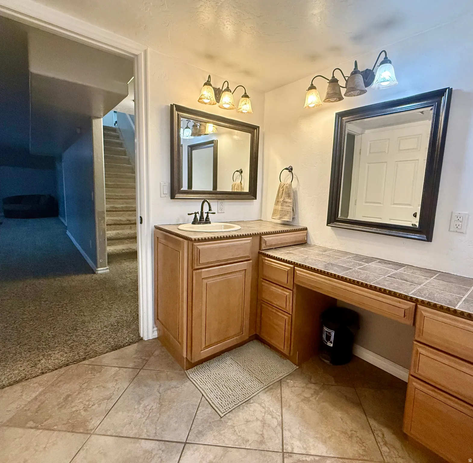 Vanity area featuring a built-in sink with a single-handle faucet, tile countertop, and wood-finish cabinetry